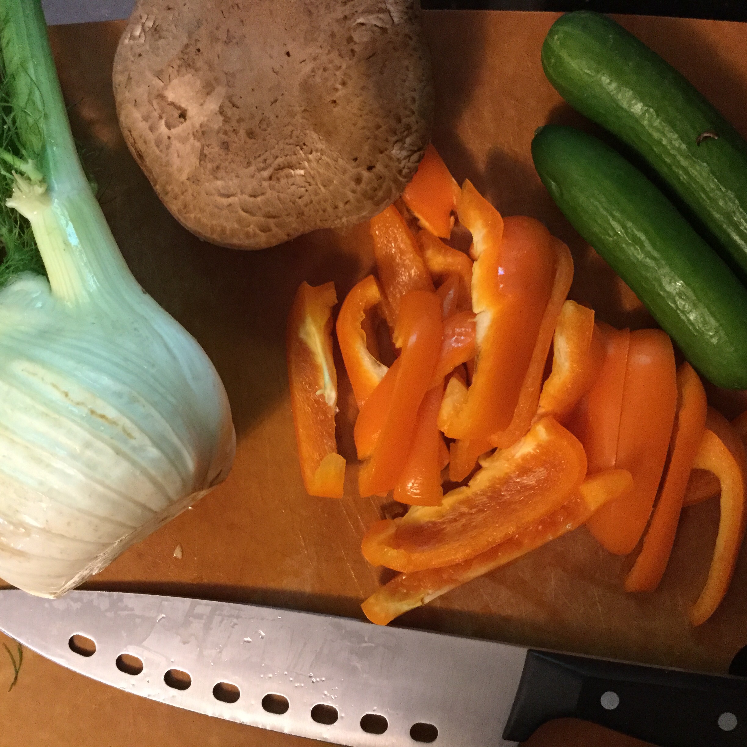 Cutting board, chef knife, fennel, portobello, cucumbers, peppers