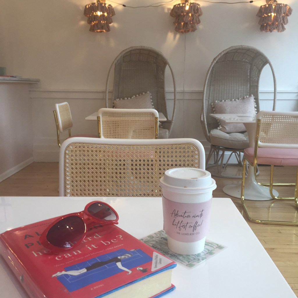 photo of book, sunglasses and cup of coffee on top of a table