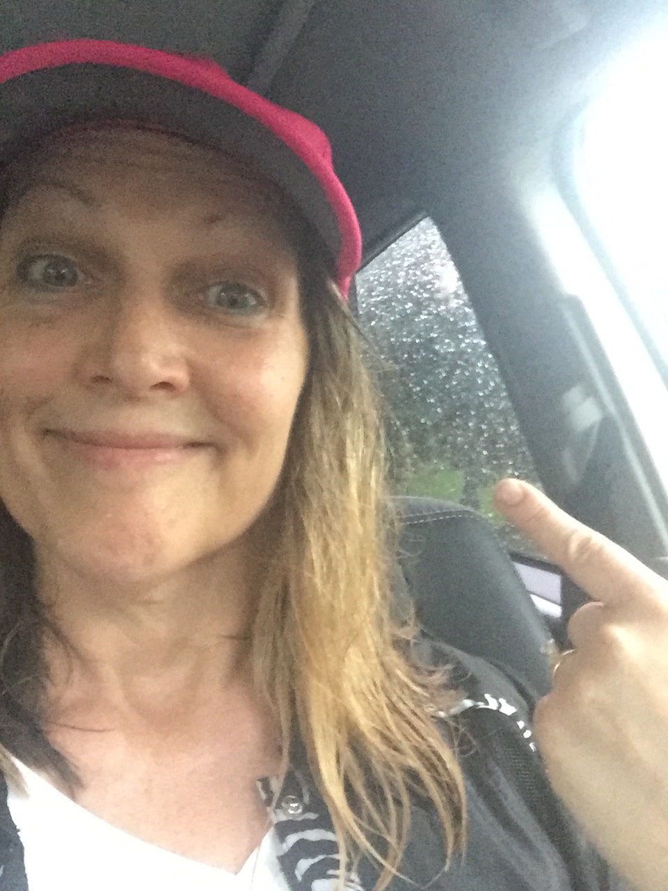 Female in car with baseball cap and wet hair 