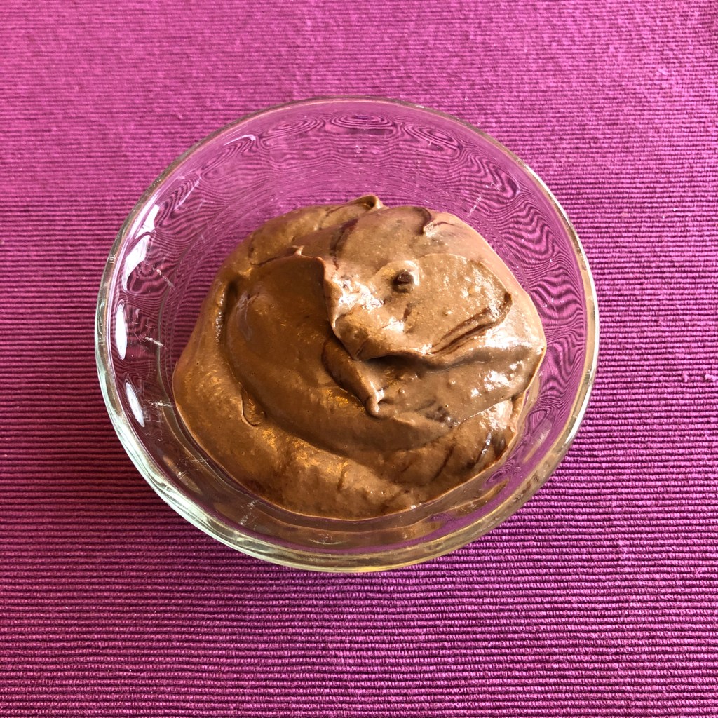 plant-based chocolate mousse served in clear custard bowl on a purple background