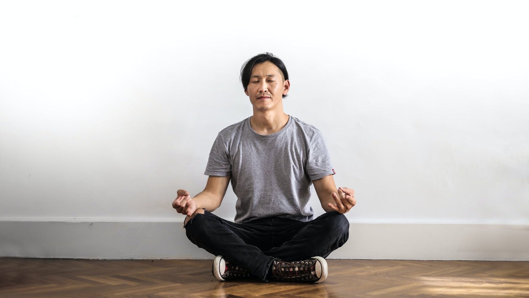 photo of man meditating in cross leg position on floor