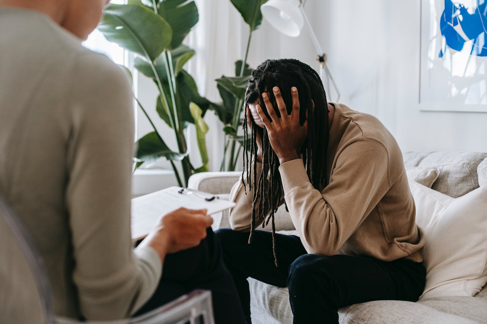 Photo of person with hands on head talking to person holding clipboard
