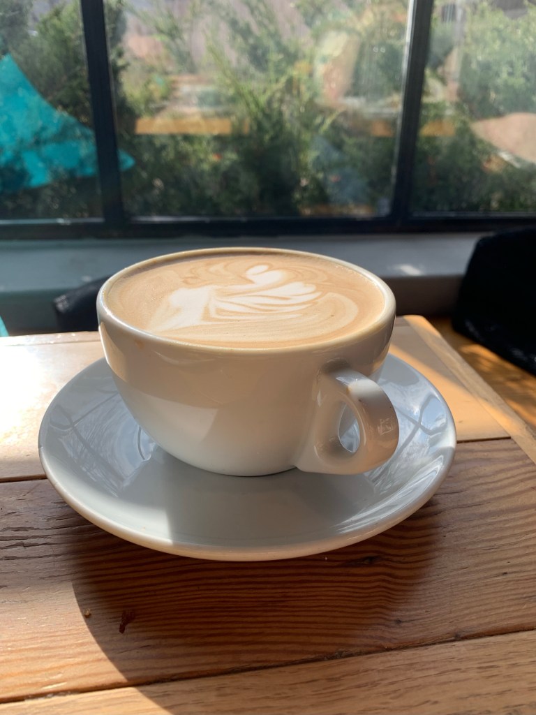 Photo of a cup of oat cappuccino with a design on top of foam