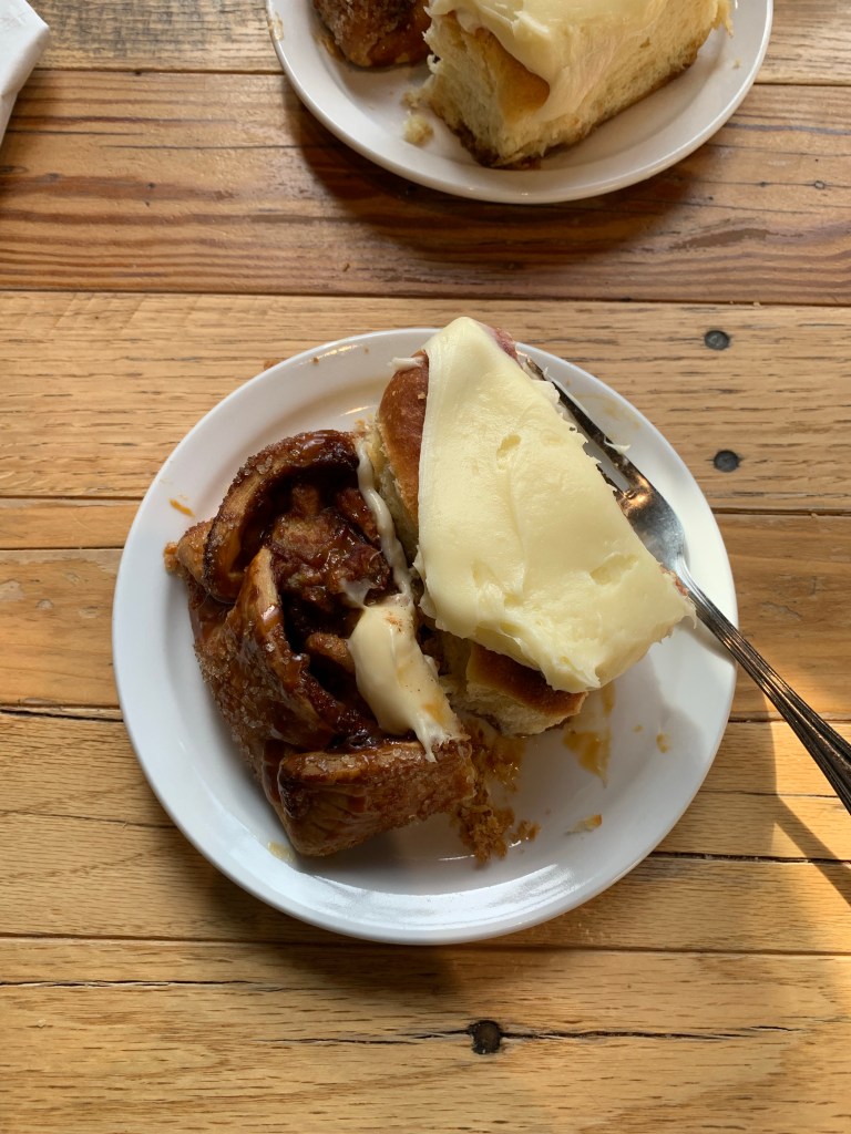 Photo of a plate with a half serving of an apple crostata and a cinnamon bun with icing